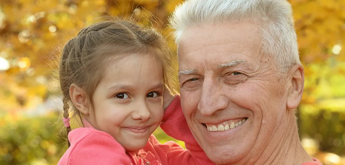 A smiling grandfather hugs his granddaughter